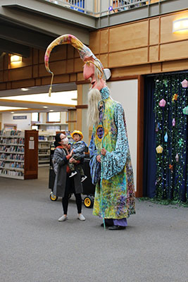 Giant wizard towers over an adult holding a child.