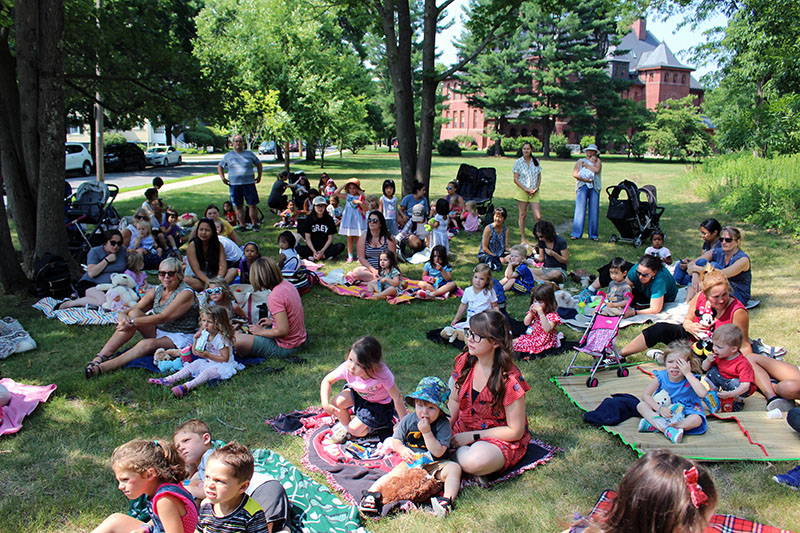 Families sitting on lawn blankets outside.