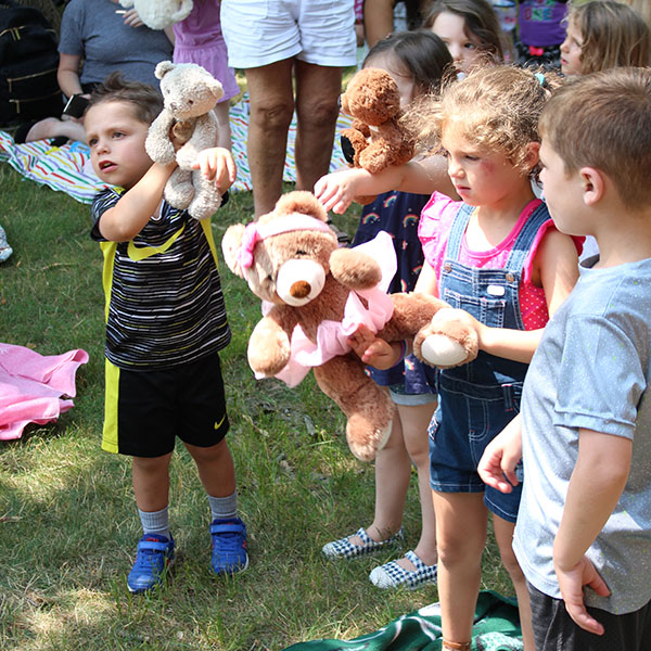 Children standing and holding their stuffed bears up high.