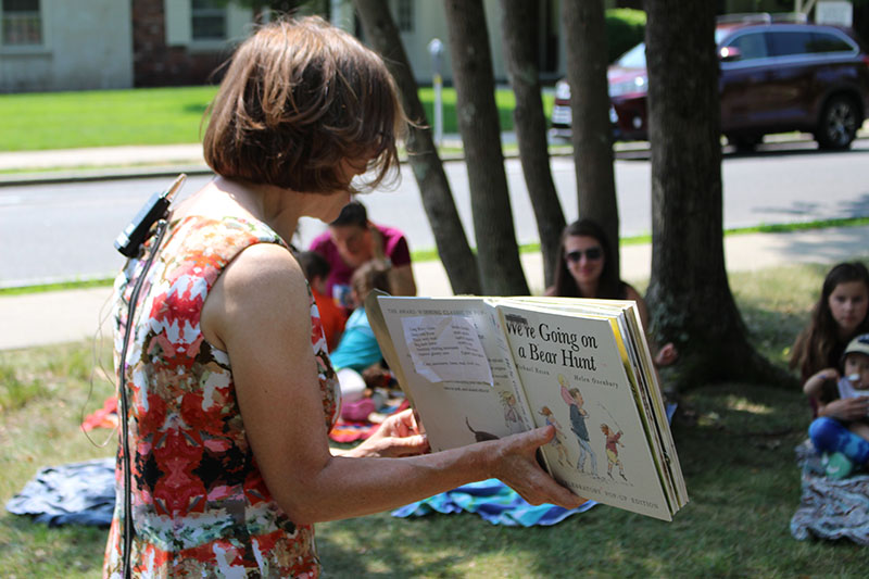 Ita reading "We're Going on a Bear Hunt" to families outside.