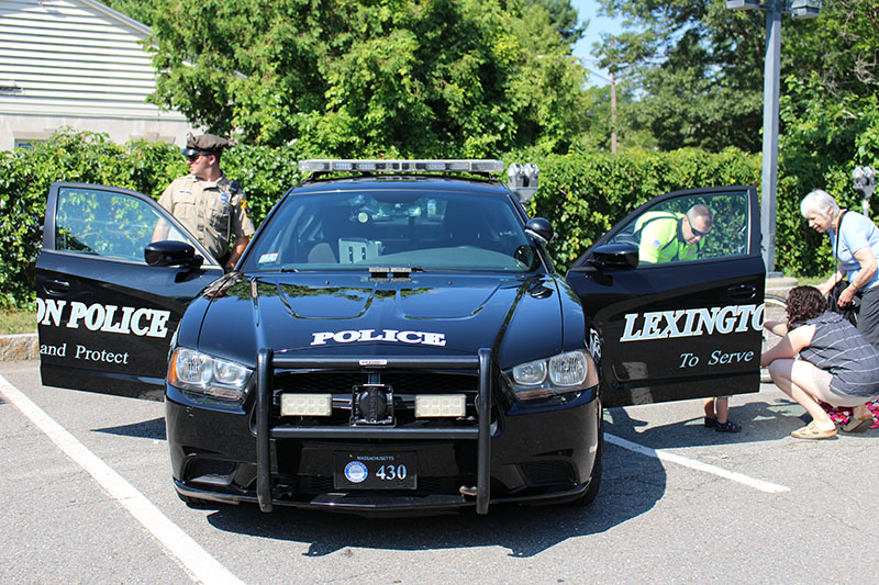 Police officers showing their police car to children and parents.