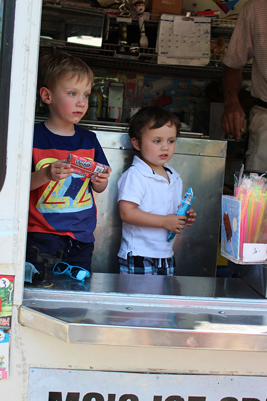 Two children holding treats inside an ice cream truck.