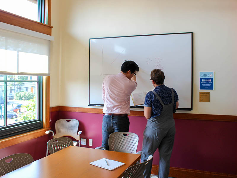 Two people at whiteboard in study room
