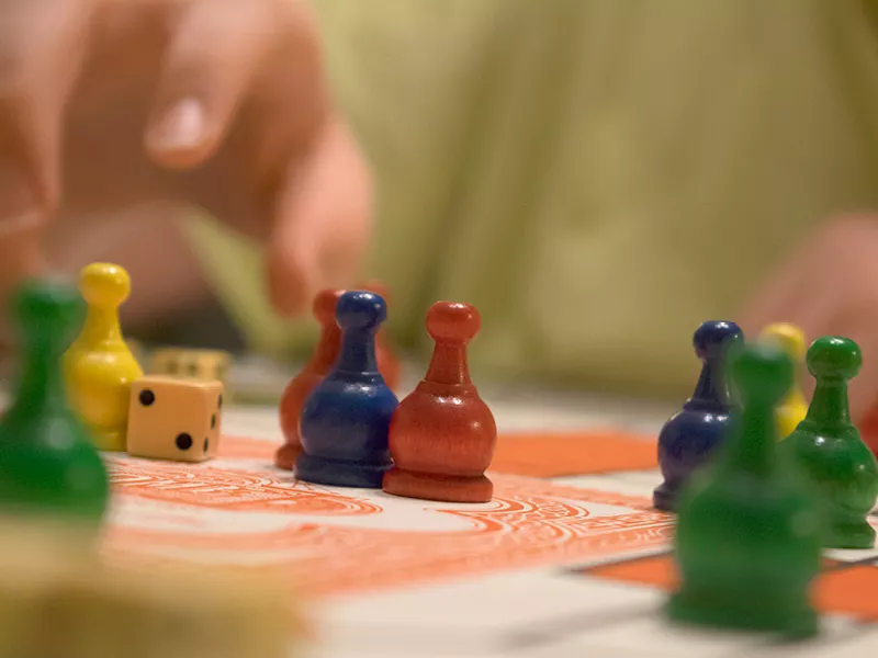 Closeup of a child's fingers about to grab one of many multicolored game pieces