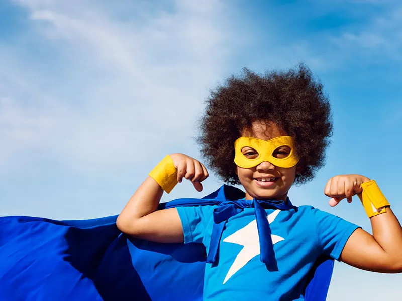 Child in a blue superhero costume, cape, and yellow mask
