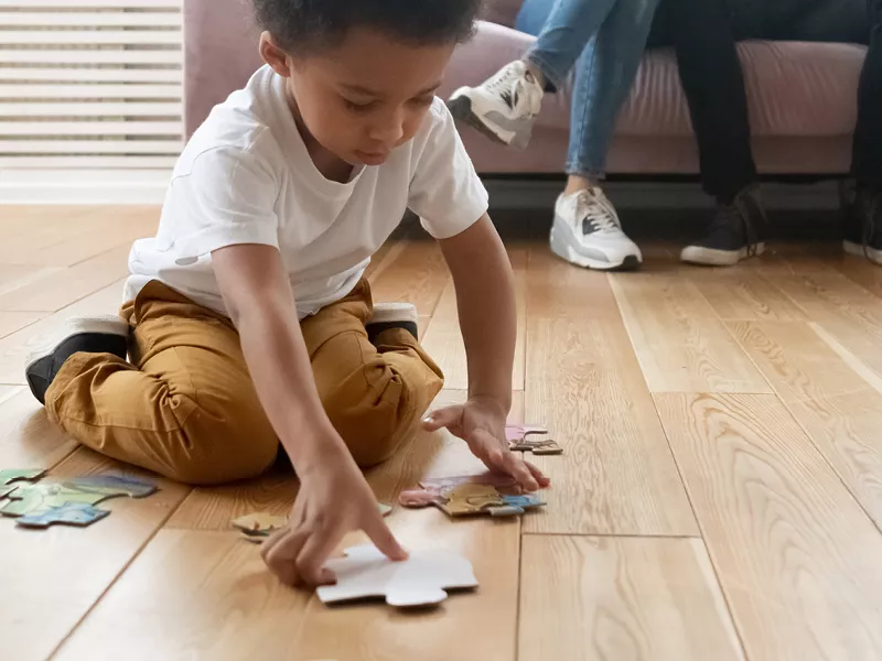 Child with a large puzzle piece on the floor